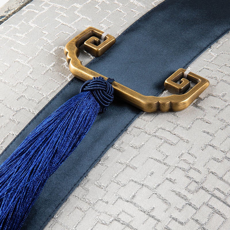Gold clasp at centre of silver &amp; navy cushion